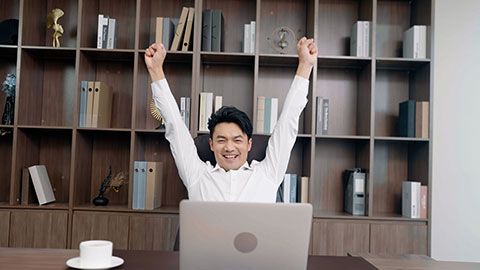 Cheerful Chinese businessman stretching in office