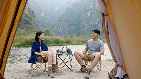 Happy young Chinese couple camping outdoors