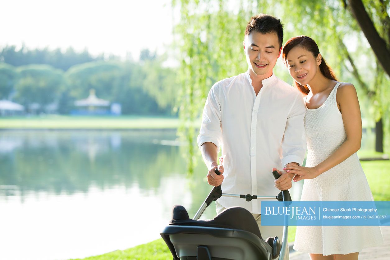 Young Chinese couple taking a walk with their baby in pram