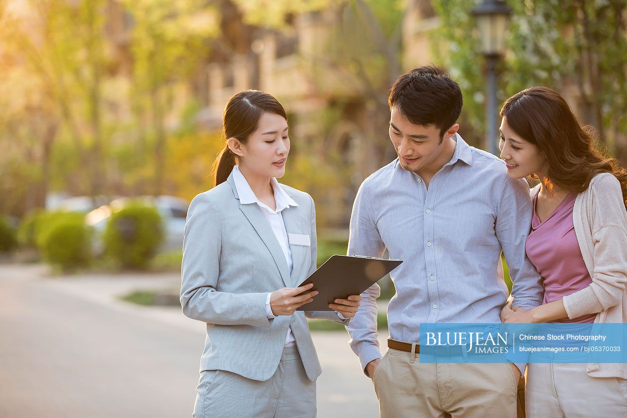 Happy young Chinese couple talking with realtor-High-res stock photo ...