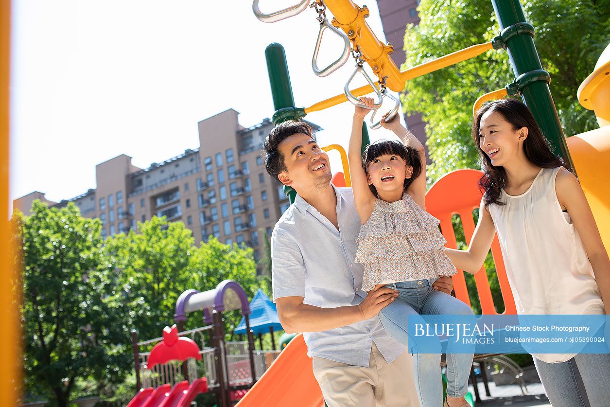 Happy young Chinese family playing in amusement park