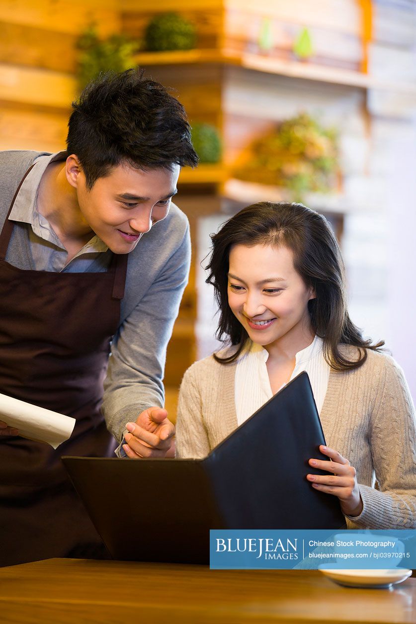 Chinese waiter taking order from woman at restaurant
