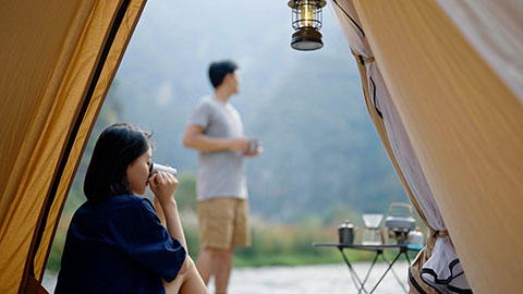 Happy young Chinese couple camping outdoors