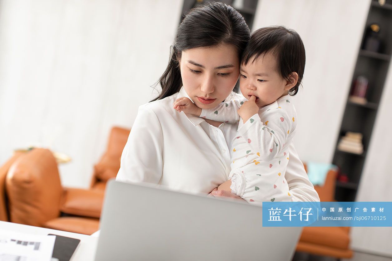 忙碌的妈妈在家边工作边照顾宝宝