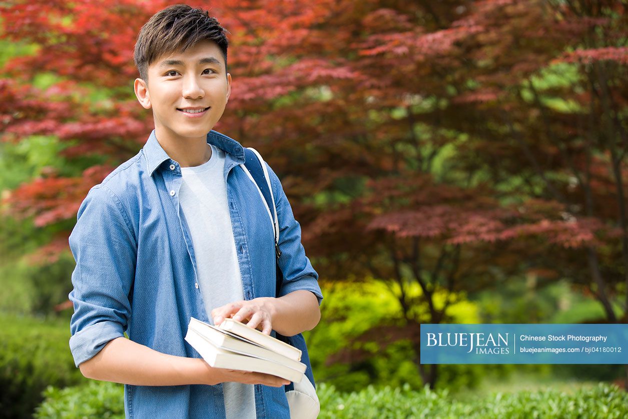 Happy male Chinese college student with books