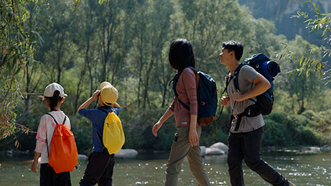 Happy young Chinese family hiking outdoors