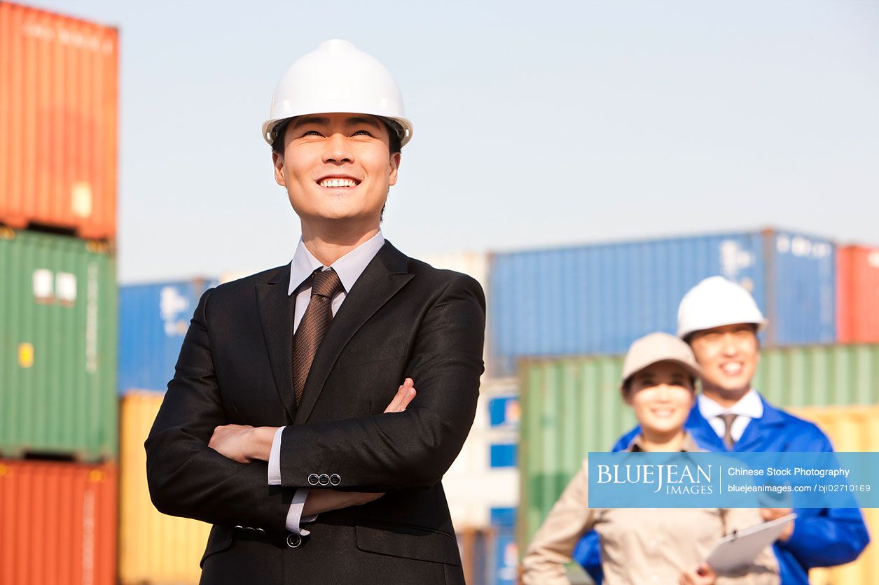 Chinese businessman with shipping industry workers in the background