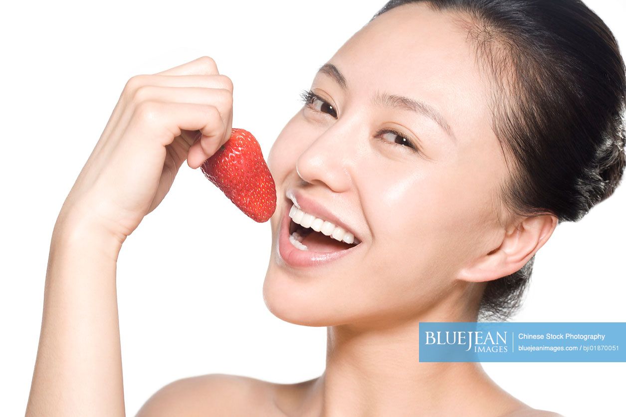 Young Chinese woman eating strawberry