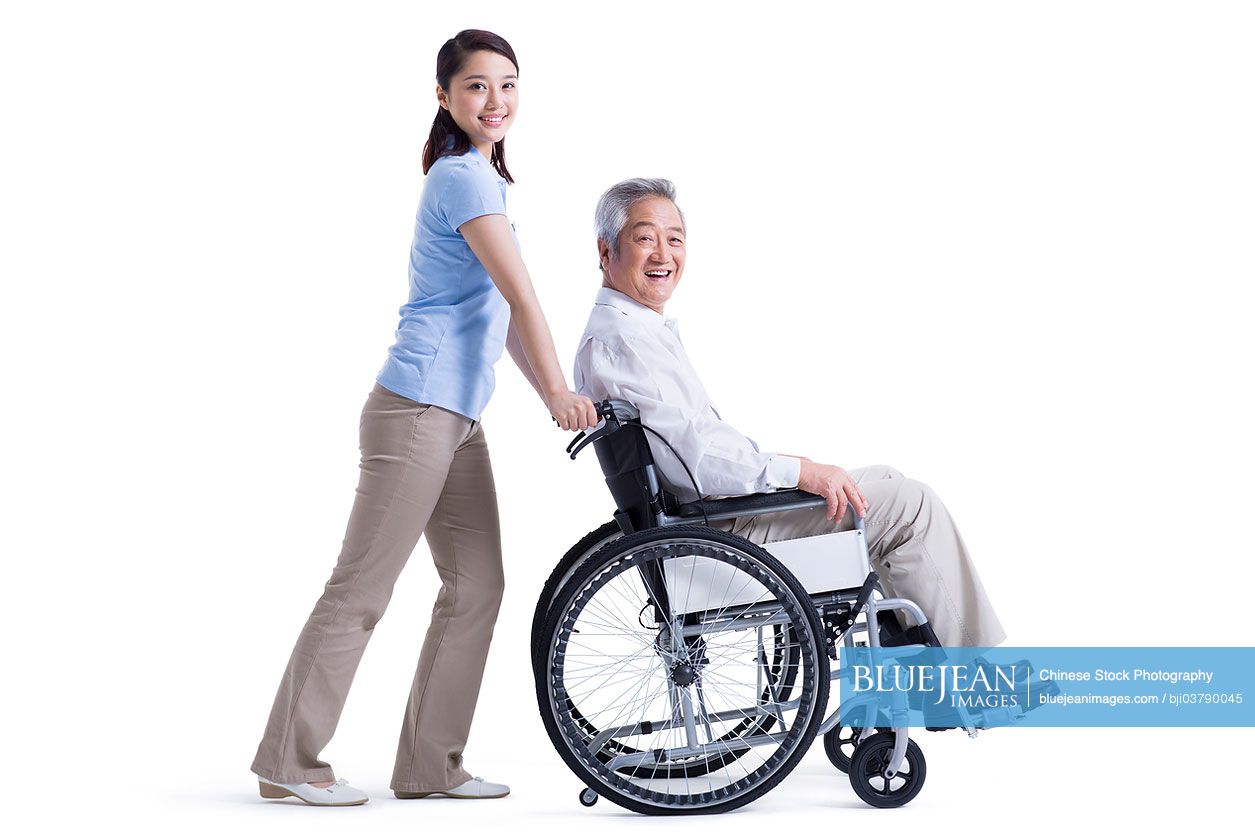 Chinese female nursing assistant taking care of senior in wheelchair