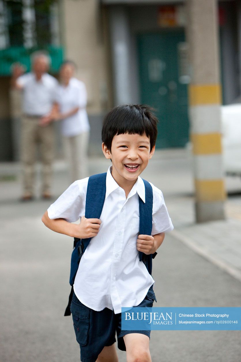 Chinese schoolboy with grandparents in background