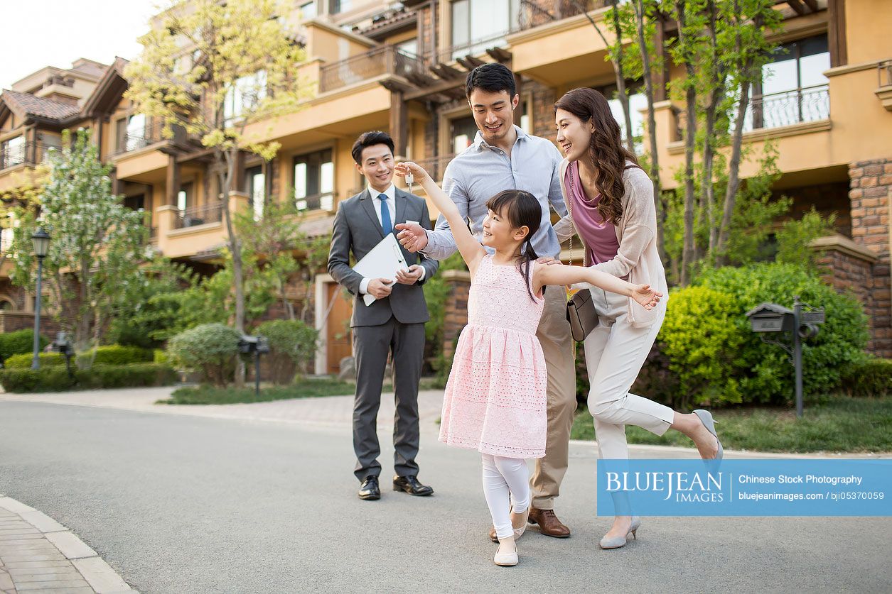 Happy young Chinese family holding keys to new house