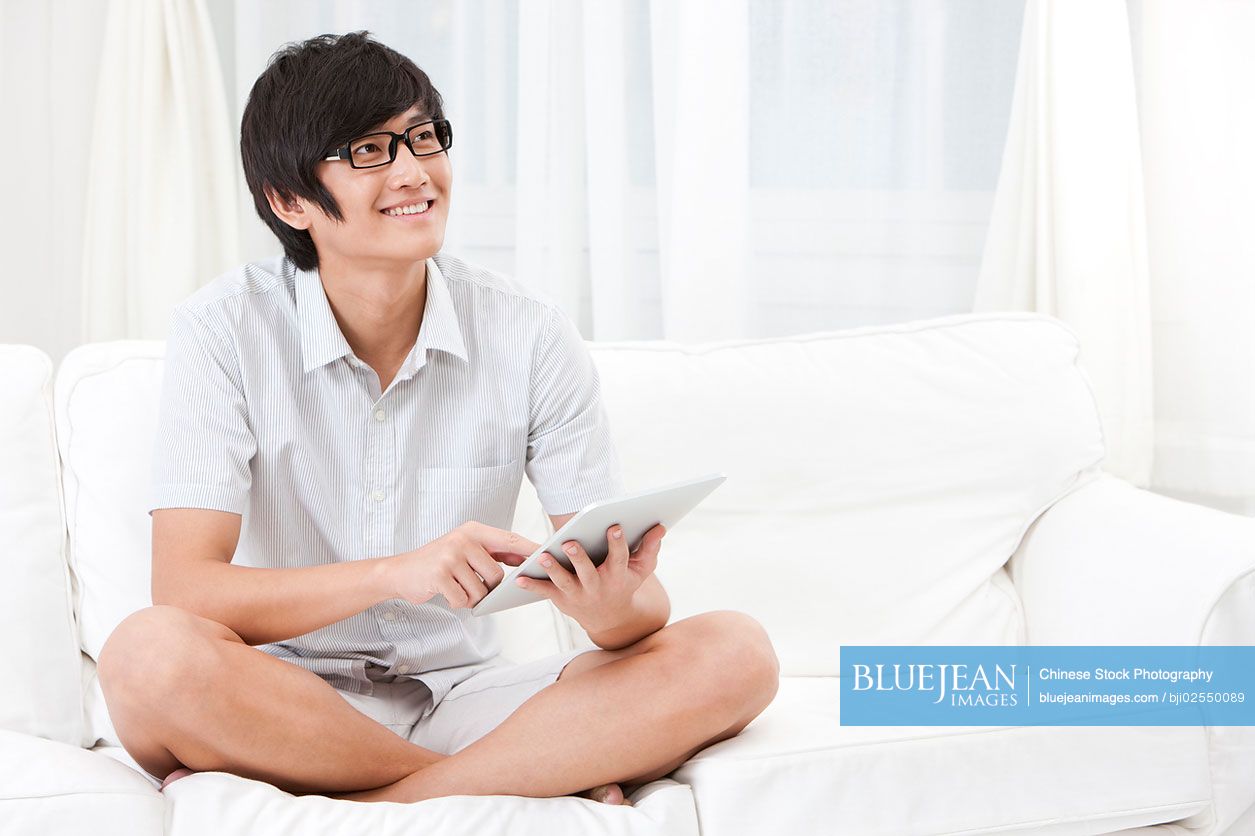 Young Chinese man using tablet at home