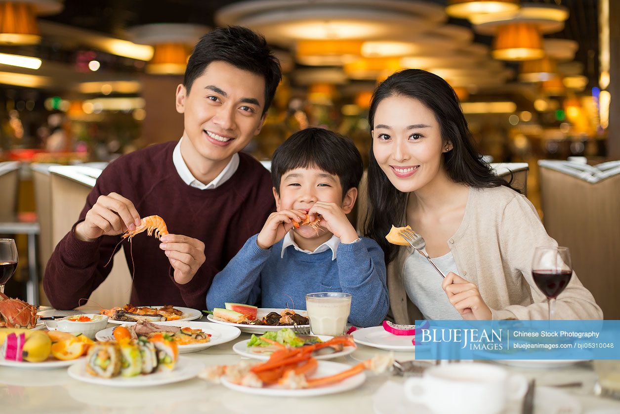 Cheerful young Chinese family having buffet dinner