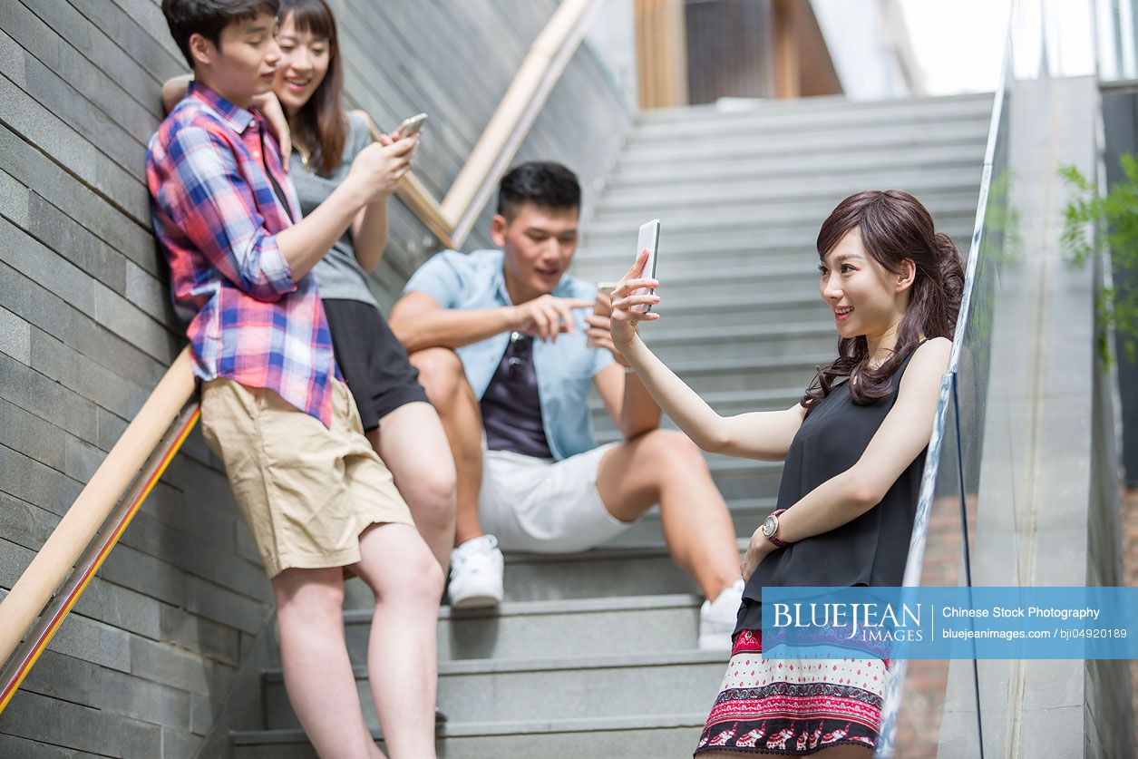 Young Chinese friends looking at smart phones