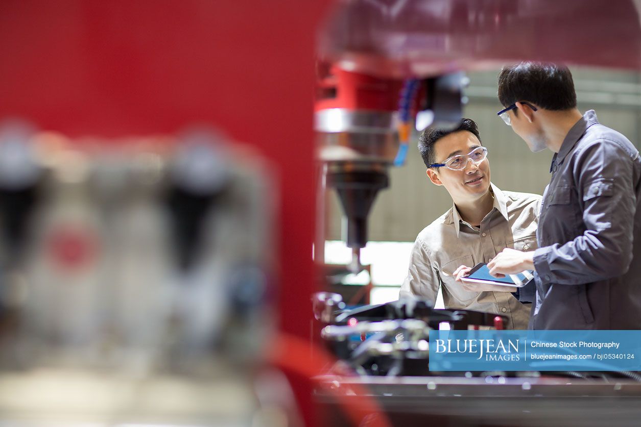 Young Chinese engineers talking in the factory