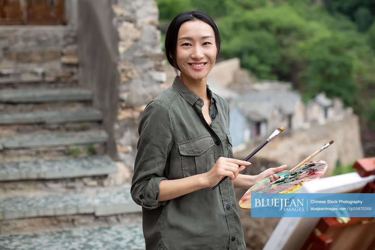Young Chinese artist painting outdoors