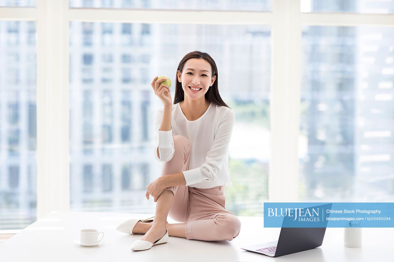 Young Chinese businesswoman holding an apple in office