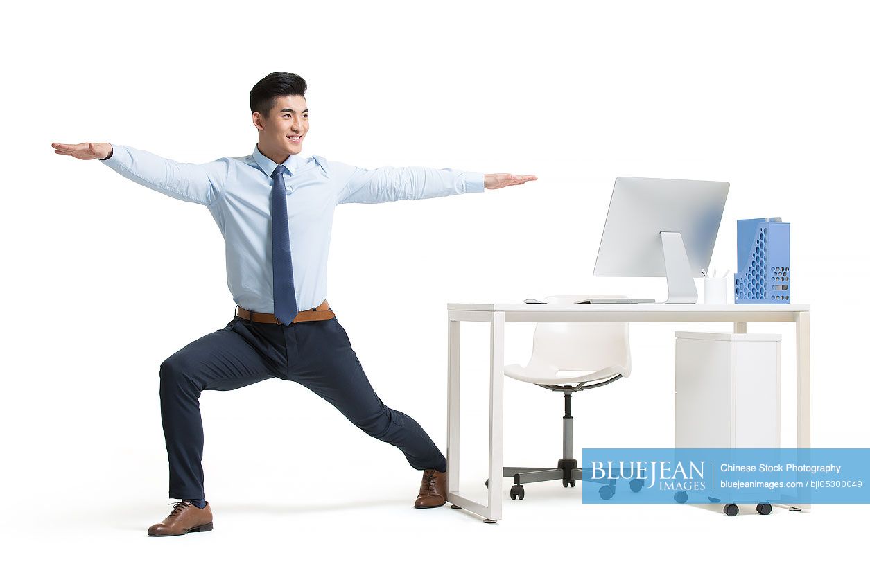 Young Chinese businessman exercising in office