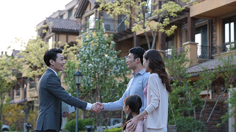 Young Chinese realtor giving house key to young family,HD