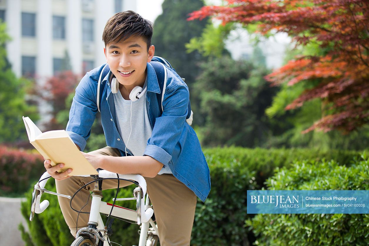 Male Chinese college student Reading on bicycle