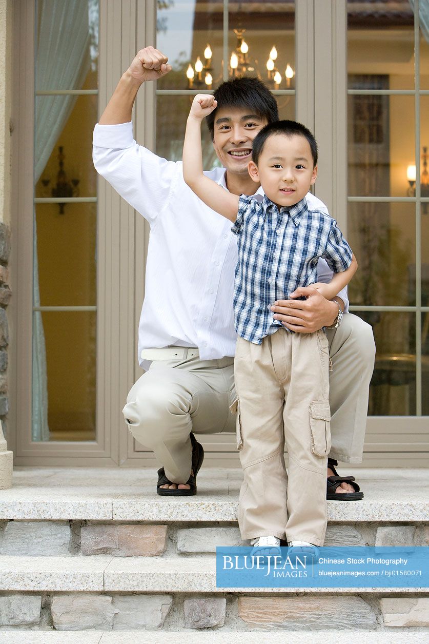 Chinese father and son having fun in front of house
