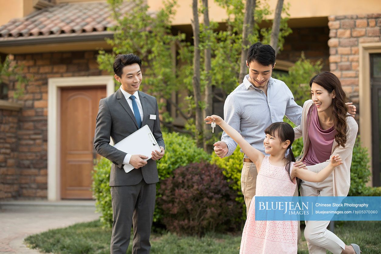 Happy young Chinese family holding keys to new house