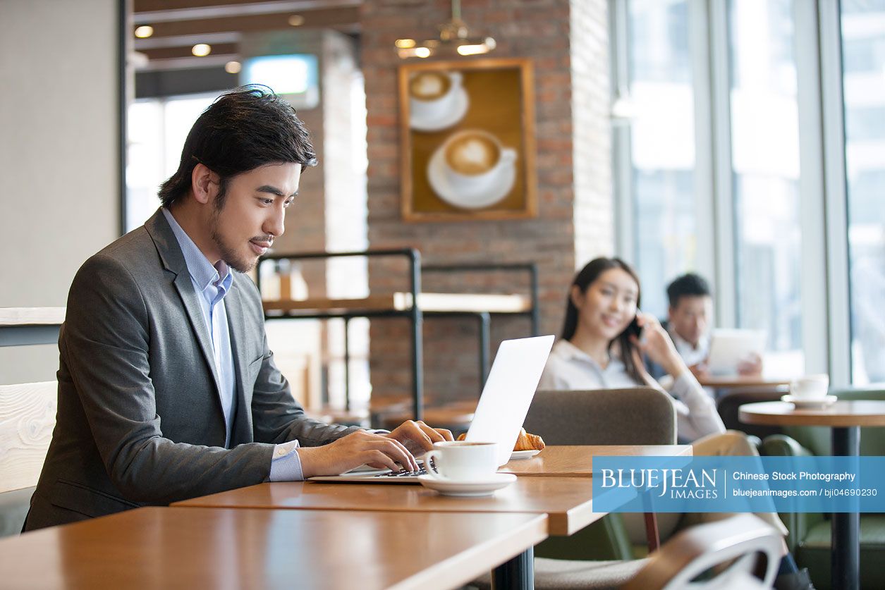 Chinese businessman working with laptop in café