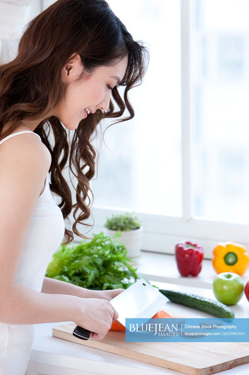 Young Chinese woman cooking in kitchen