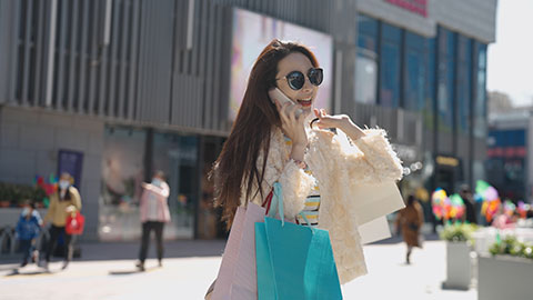 Cheerful young Chinese woman walking with shopping bags,4K