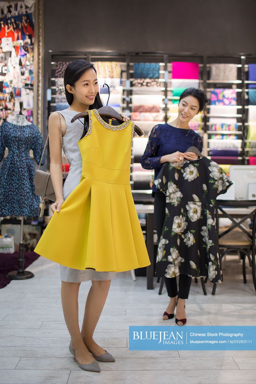 Chinese clothing store owner helping customer choosing dress
