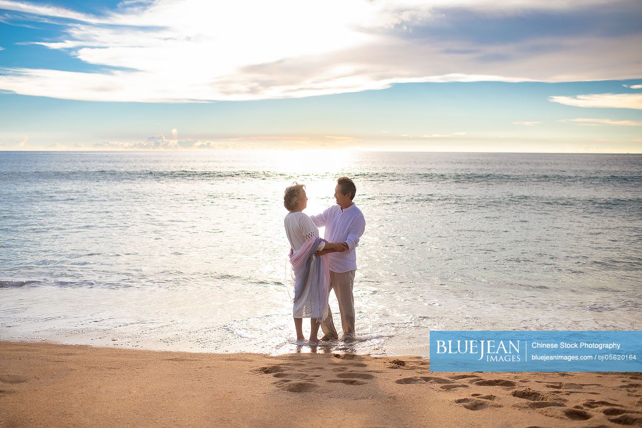 Happy senior Chinese couple on beach