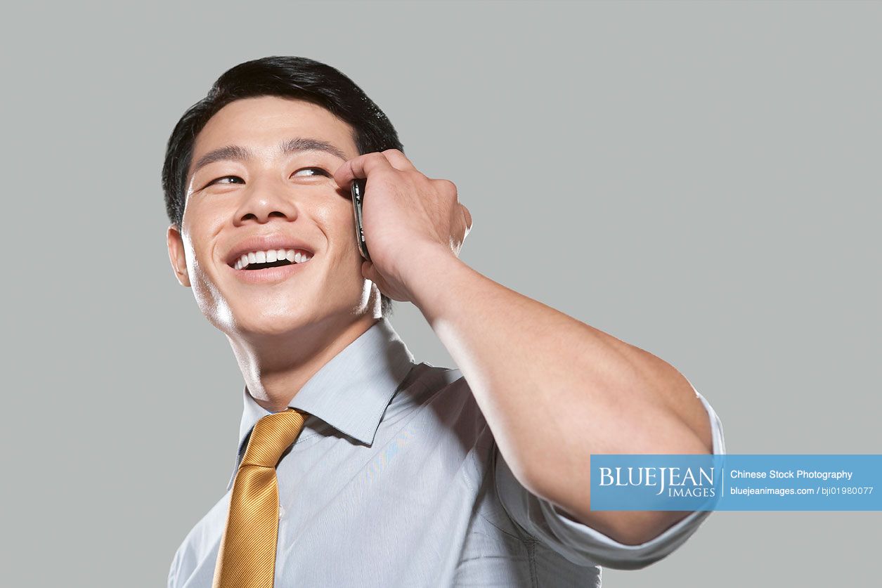 Chinese businessman talking on mobile phone, white background