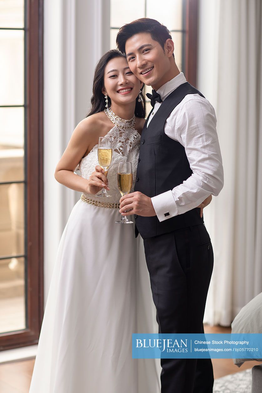 Happy young Chinese couple drinking champagne at home