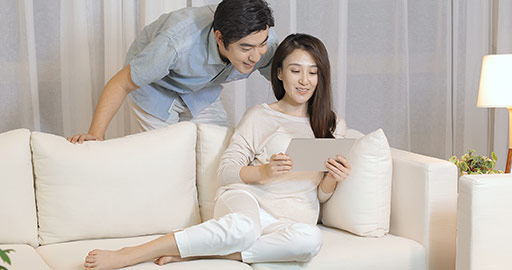 Happy young Chinese couple using digital tablet in living room,4K