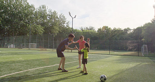 快乐的年轻家庭在足球场踢足球