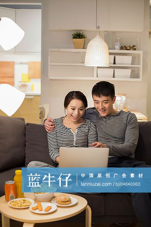 年轻情侣在客厅沙发上使用笔记本电脑