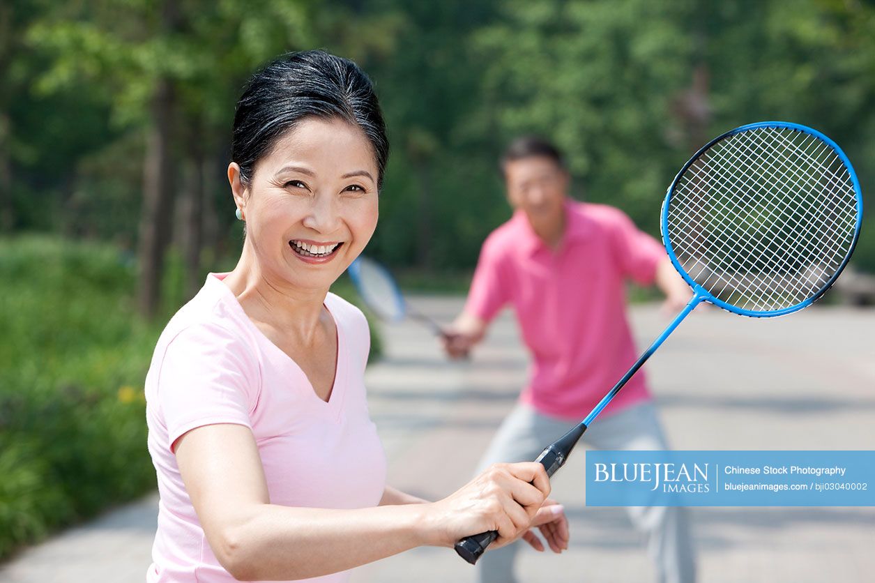 Mature Chinese couple playing badminton in park