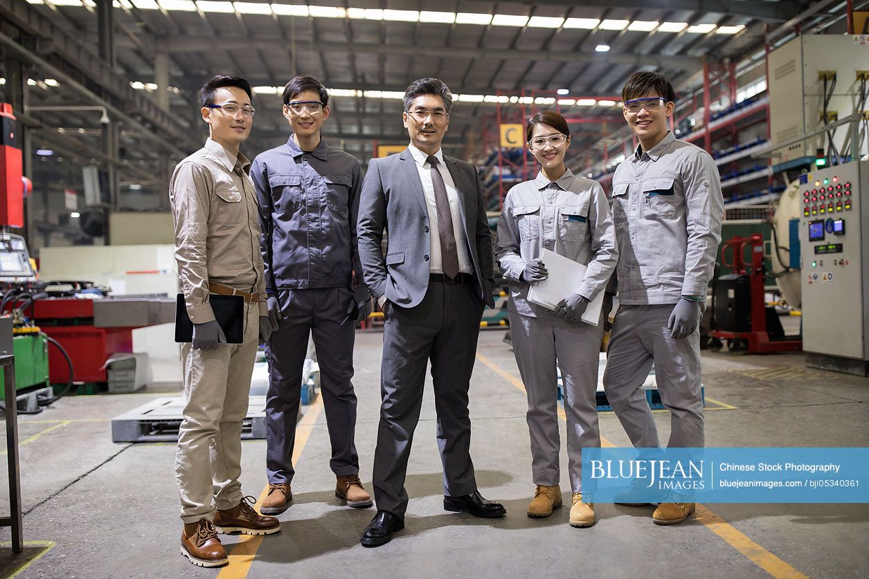 Confident Chinese businessman and engineering team in the factory