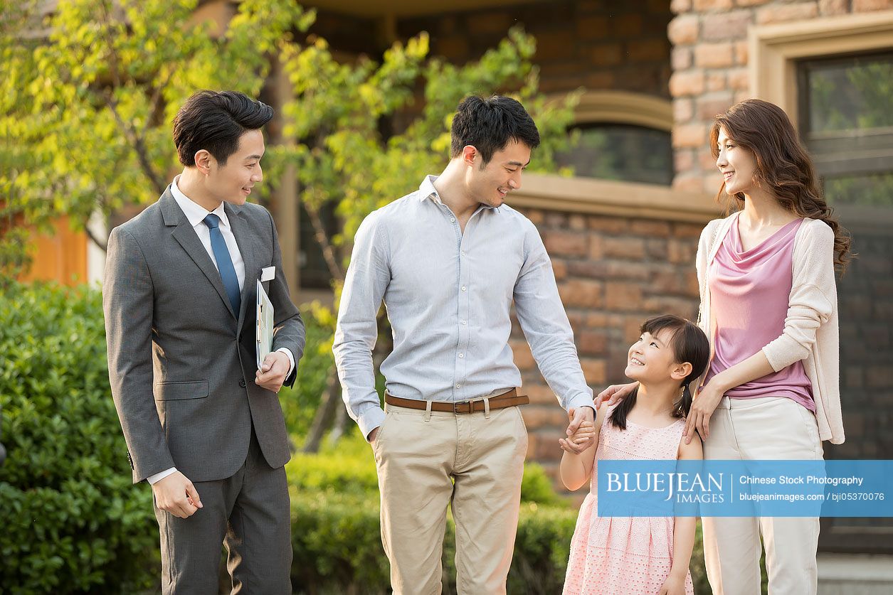 Happy young Chinese family talking with realtor