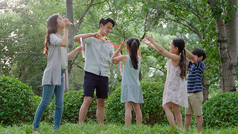 快乐年轻家庭在草地上吹泡泡