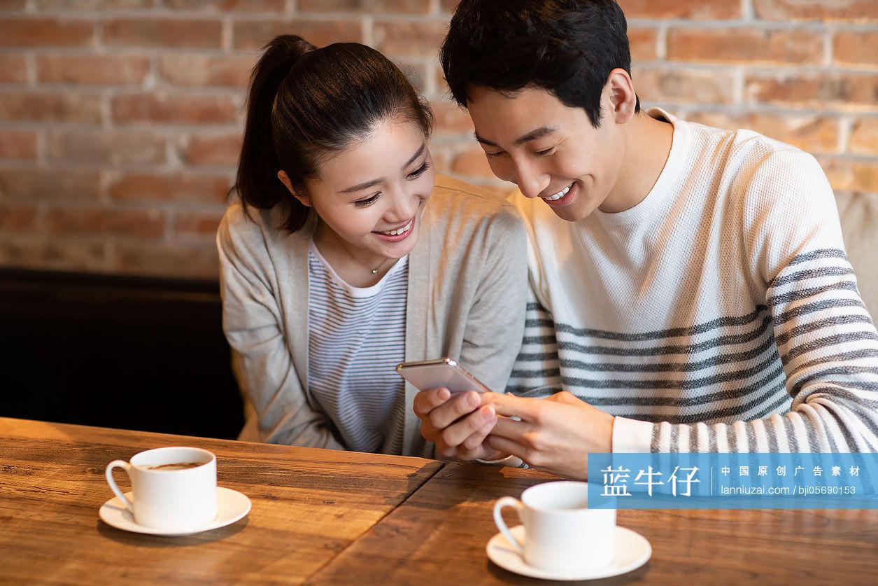 年轻情侣在咖啡店使用手机