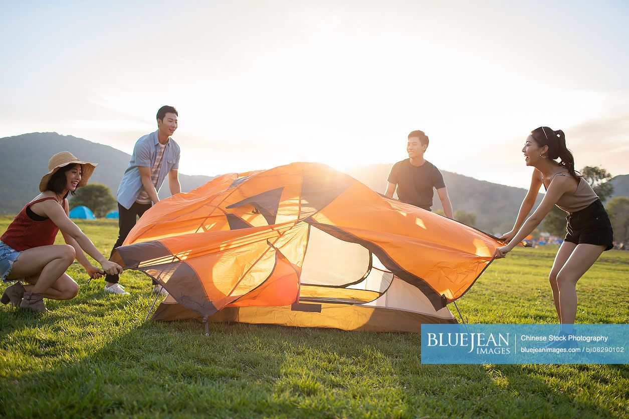 Happy young Chinese friends camping outdoors