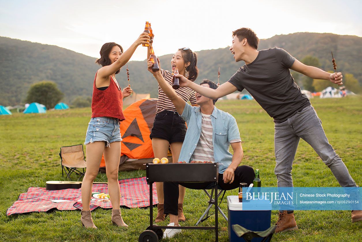 Happy young Chinese friends barbecuing outdoors