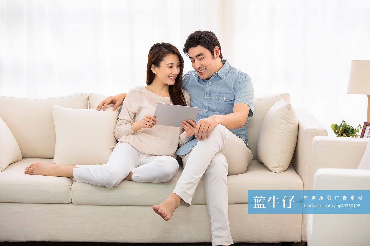 快乐的年轻情侣在客厅使用平板电脑-蓝牛仔影像-中国原创广告影像素材