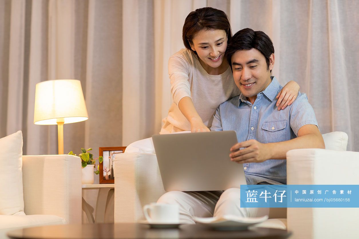 快乐的年轻情侣在客厅使用笔记本电脑
