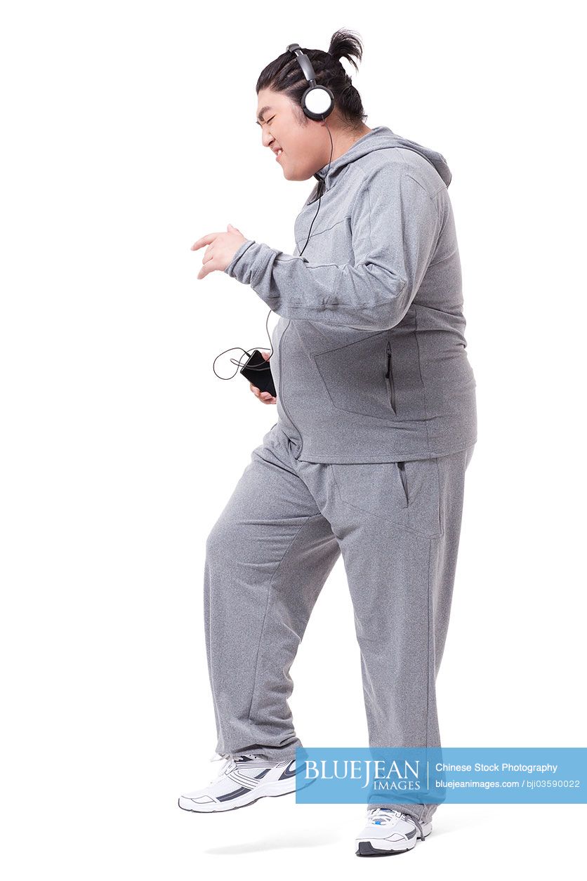 Fashionable Chubby Chinese man listening to music and dancing
