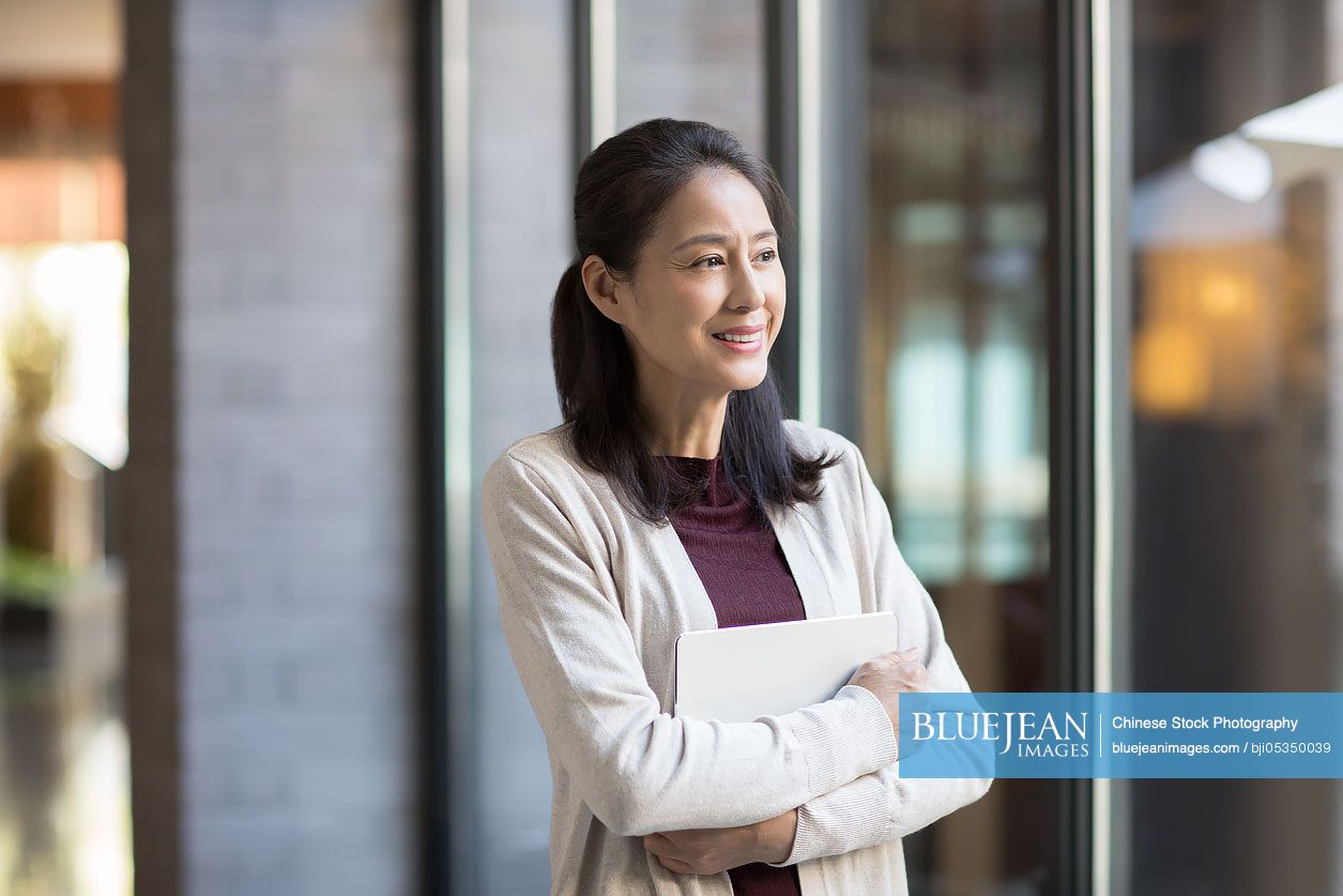 Elegant mature Chinese woman holding a digital tablet