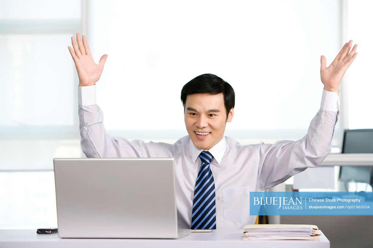 Happy Chinese office worker at his desk