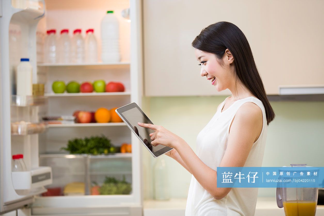 年轻女士在厨房使用平板电脑