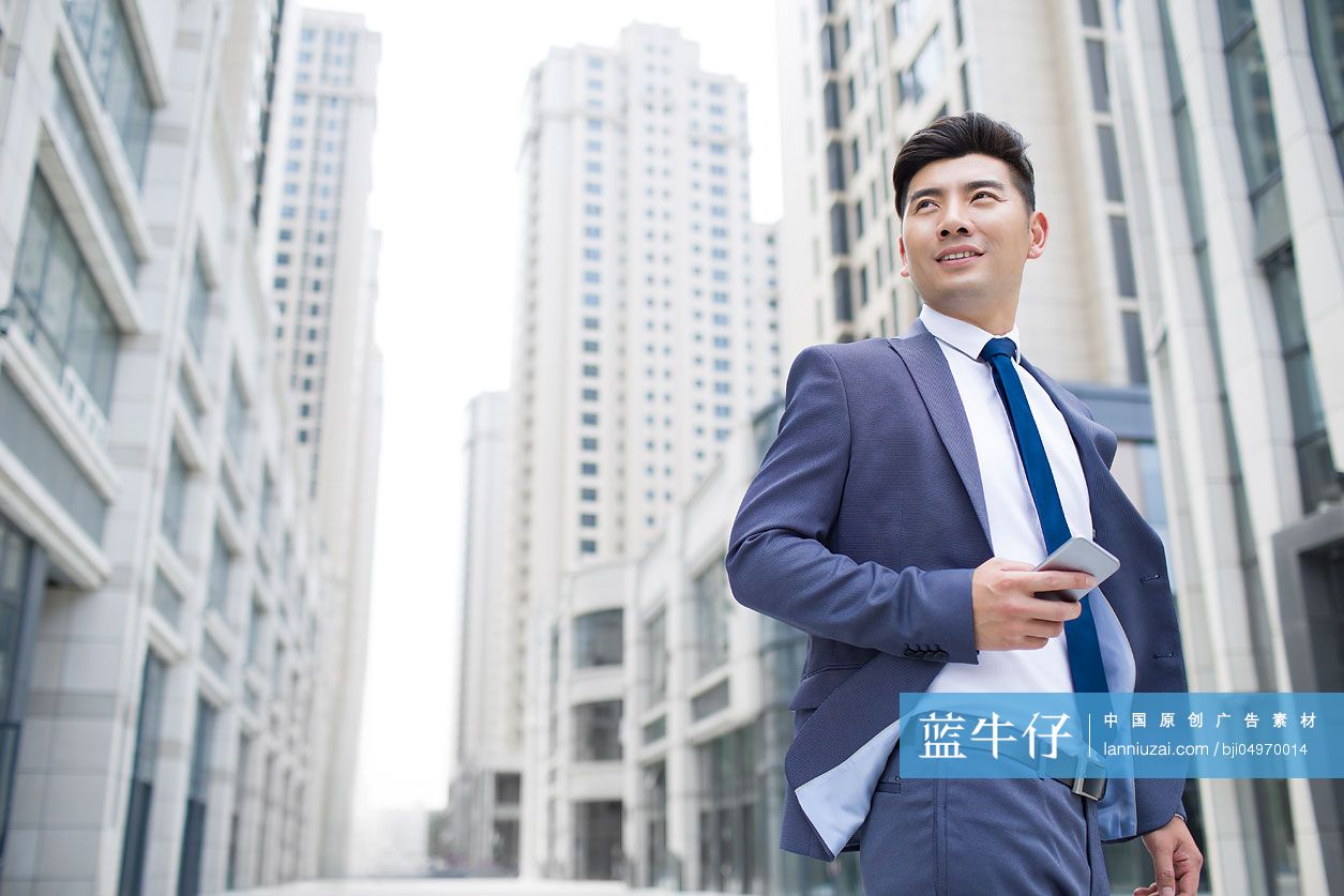 自信的商务男士拿着手机看向远方